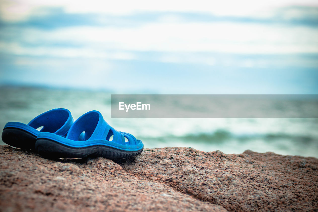 HIGH ANGLE VIEW OF SHOES ON SAND