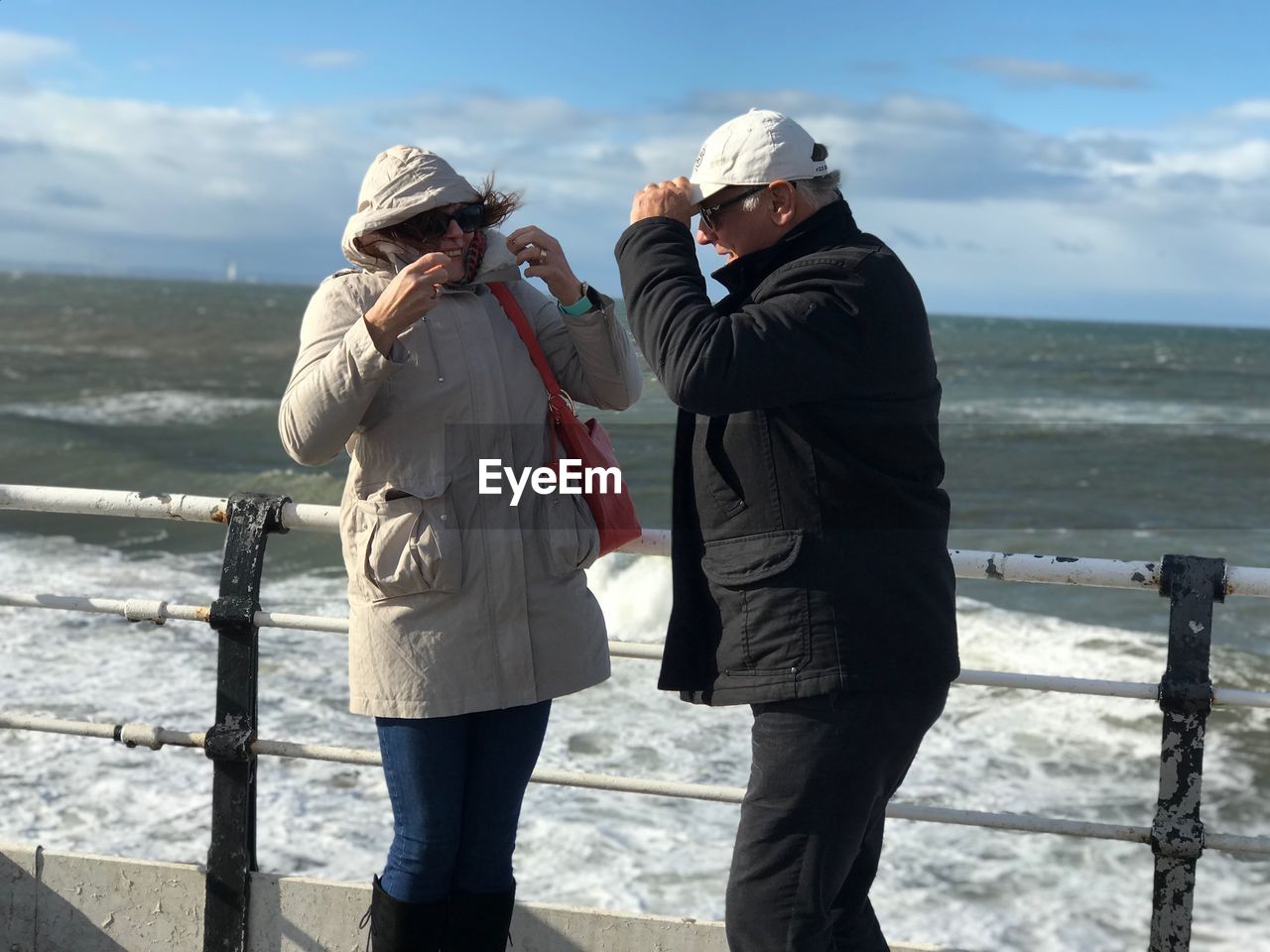Senior couple standing by sea against sky
