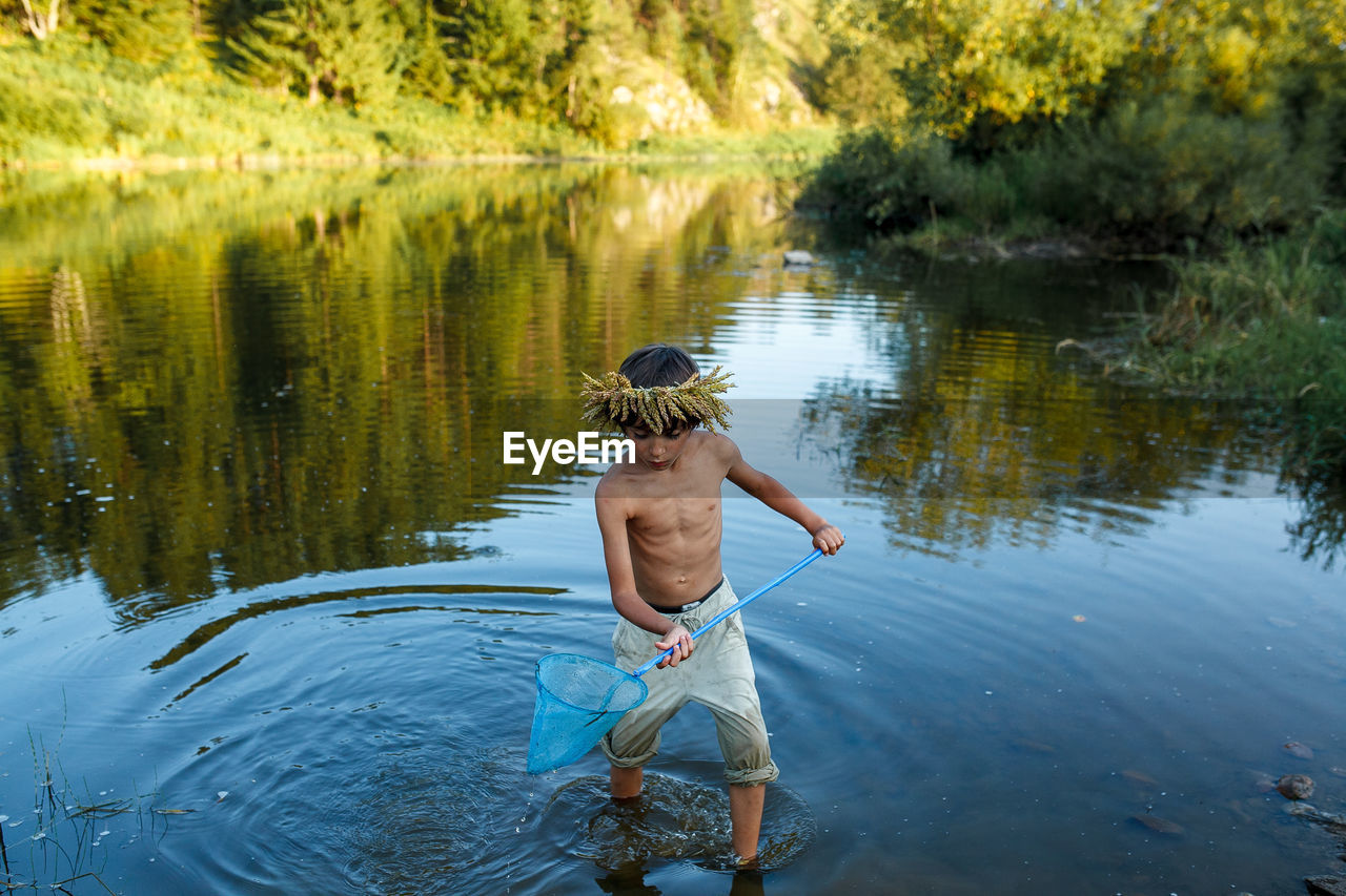 REAR VIEW OF MAN STANDING IN LAKE