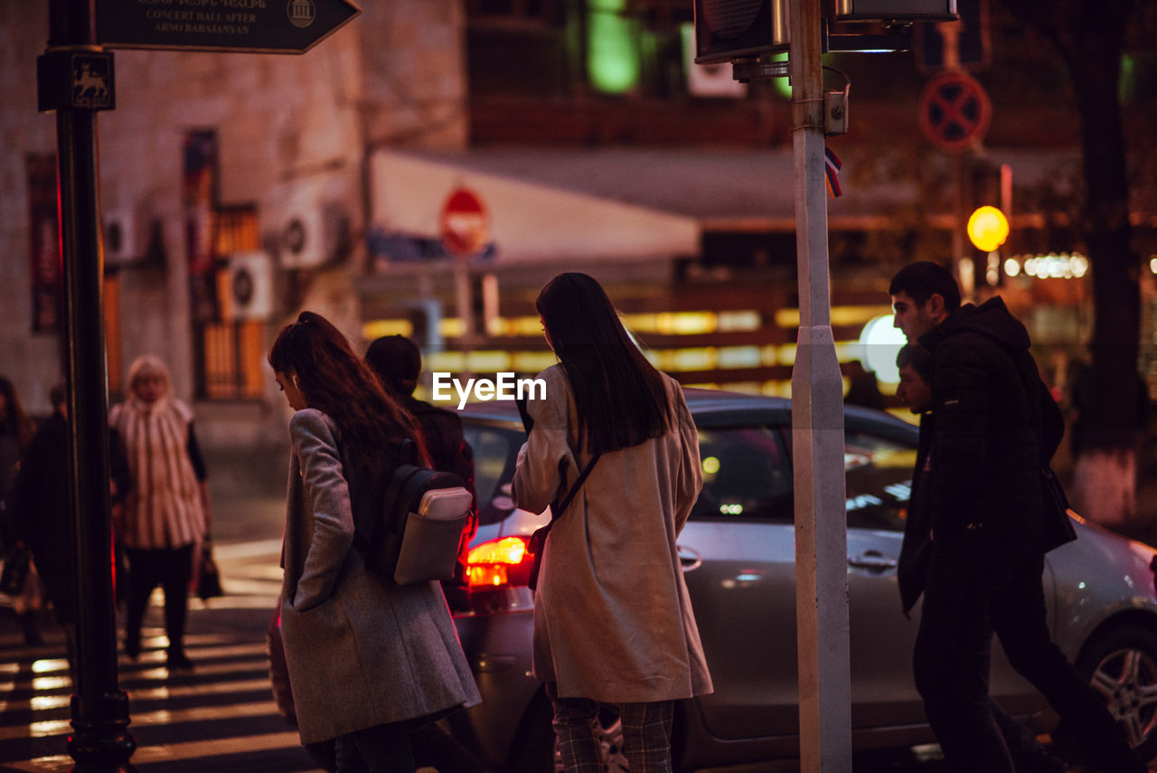 Rear view of people walking on street in city at night