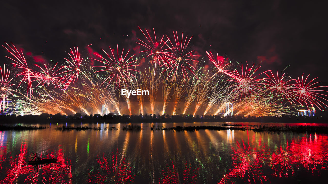 Reflection of firework display on river at night