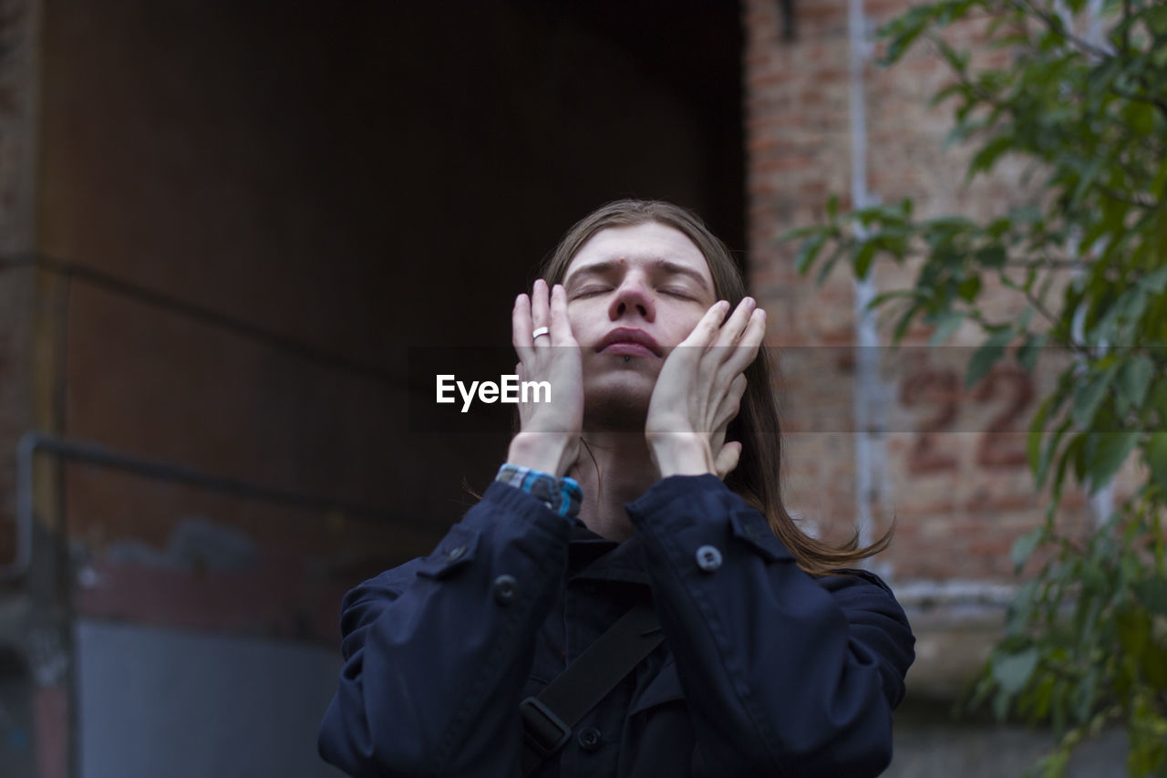 Low angle view of mid adult man with eyes closed outdoors 