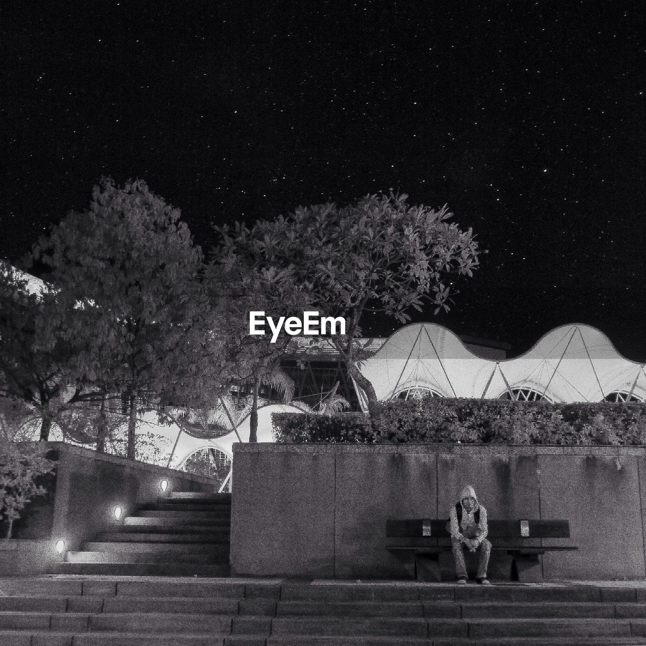 Man sitting on bench against building during night