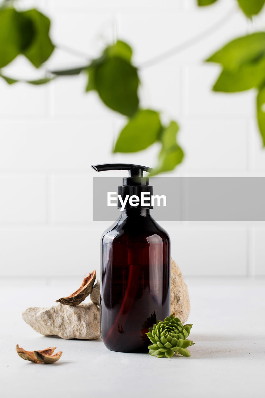 Organic cosmetic product in a brown dispenser surrounded by natural materials. 