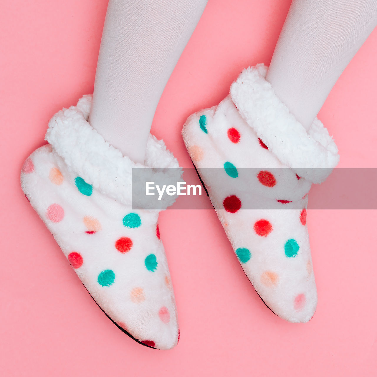 Low section view of polka dot shoes against pink background