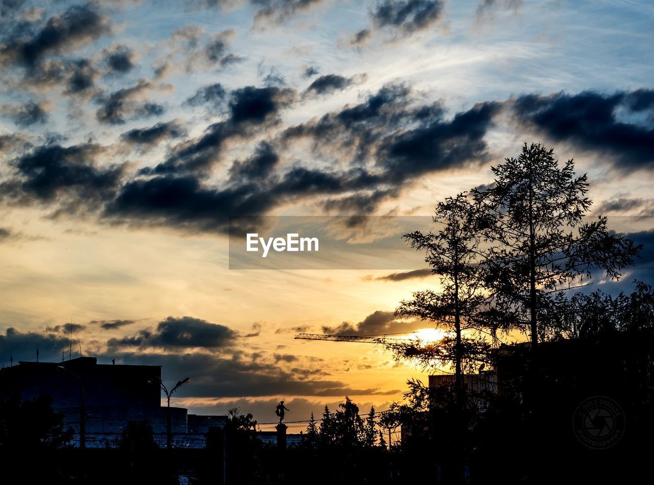 Low angle view of silhouette trees against cloudy sky