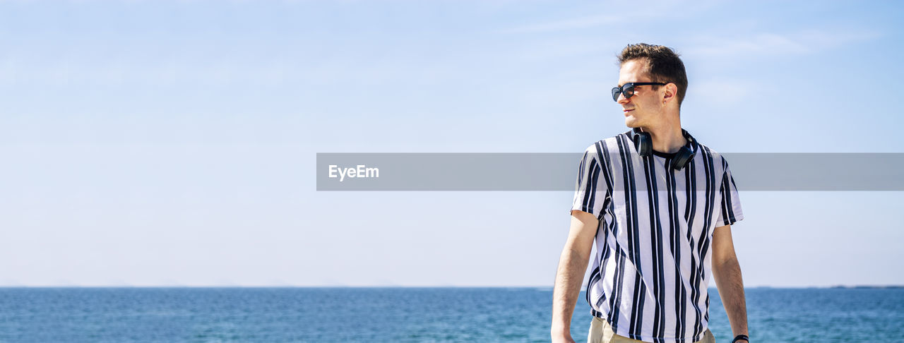 Young man with headphones relaxing on the beach