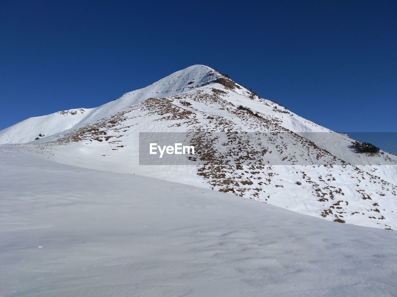 Scenic view of snowcapped mountains against clear blue sky