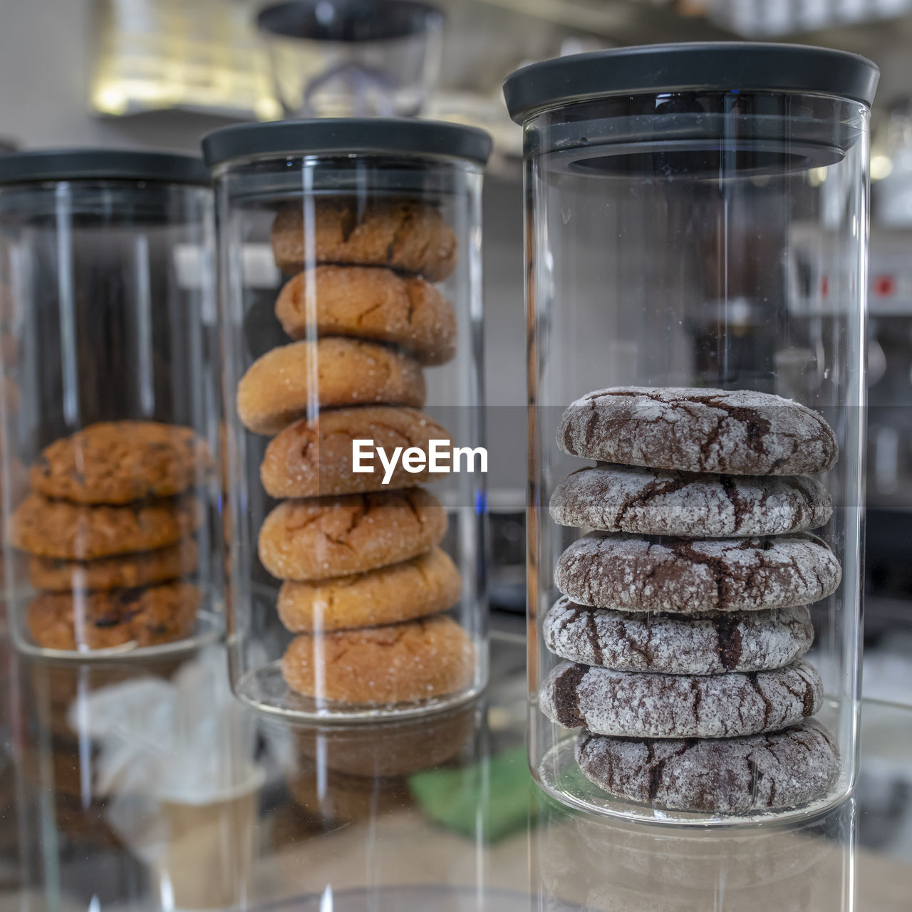 Variety of cookies in three glass jars on a counter at coffee shop.