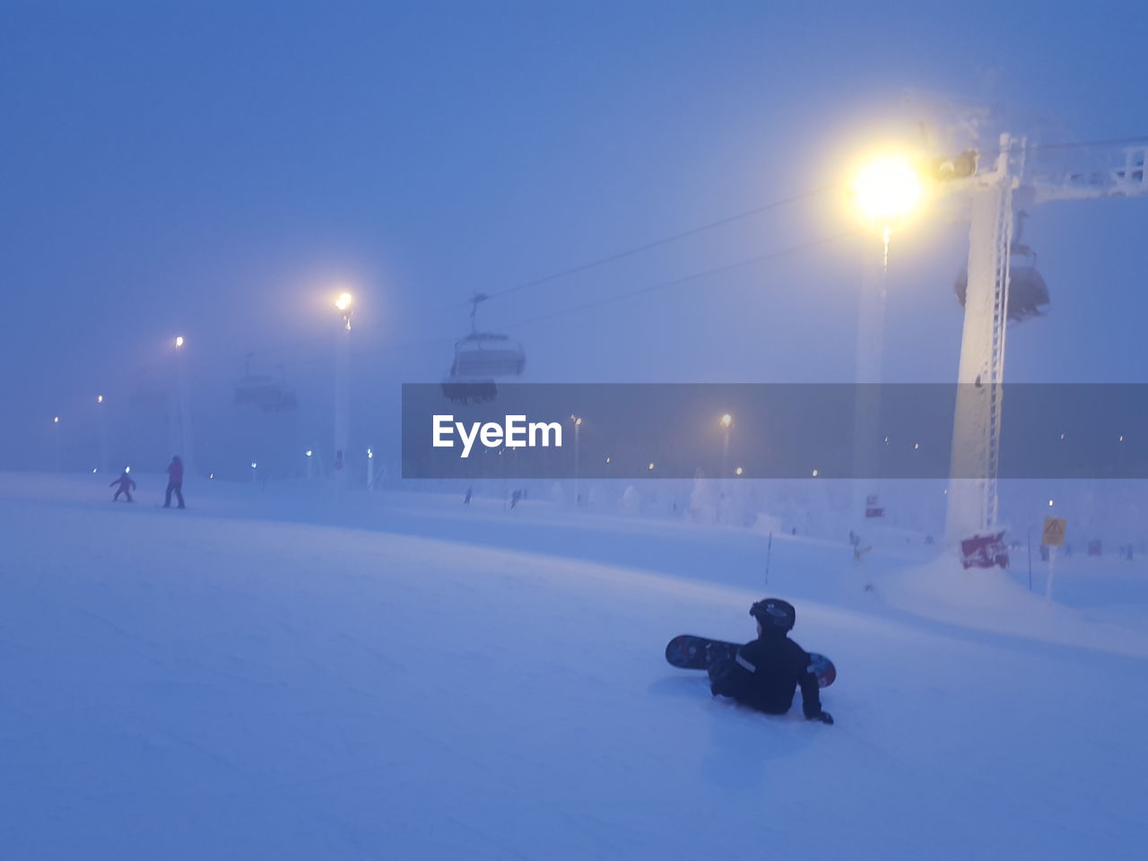 Child skateboarding on snow covered field against sky