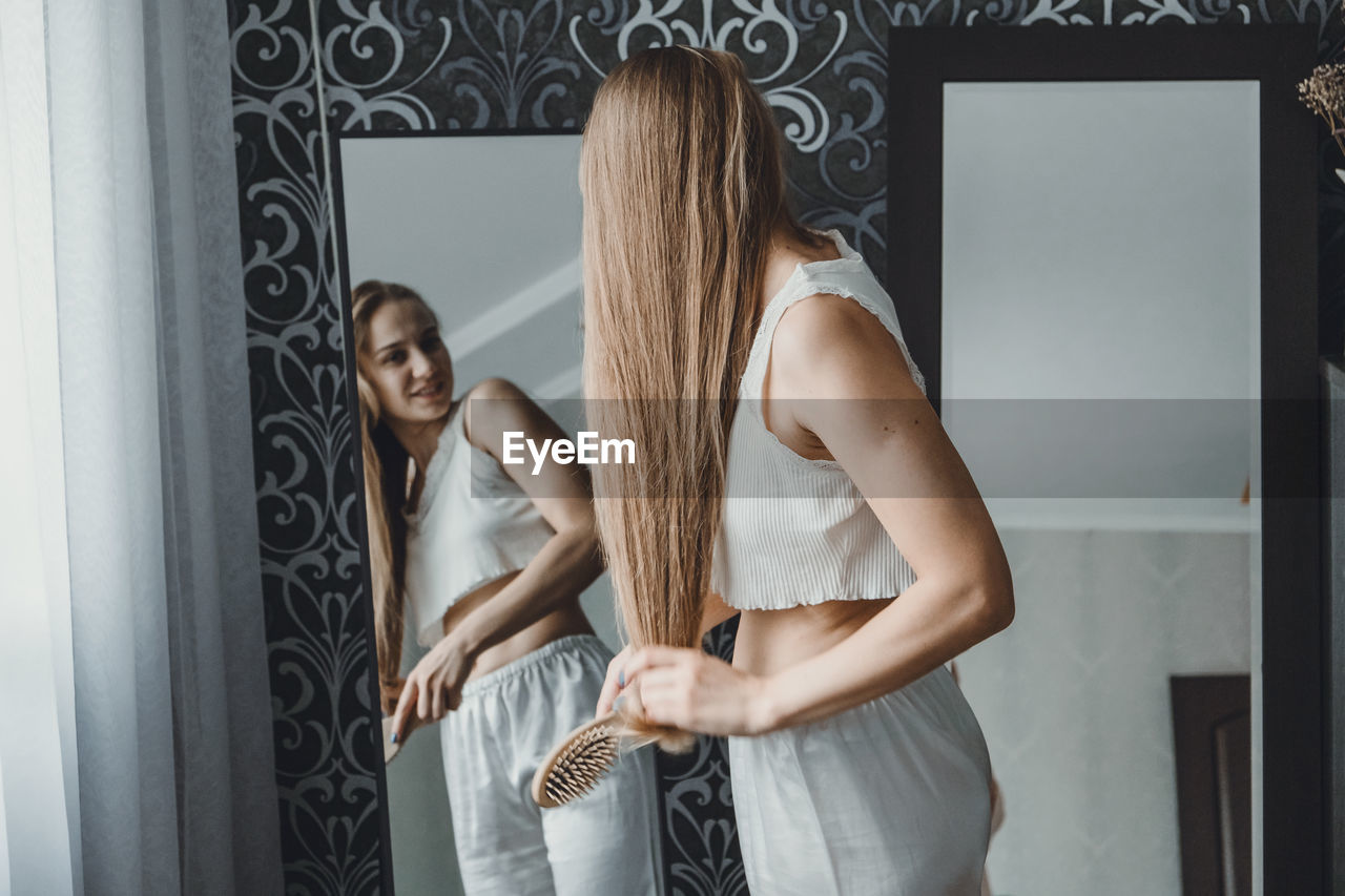 Young woman holding hair looking at mirror