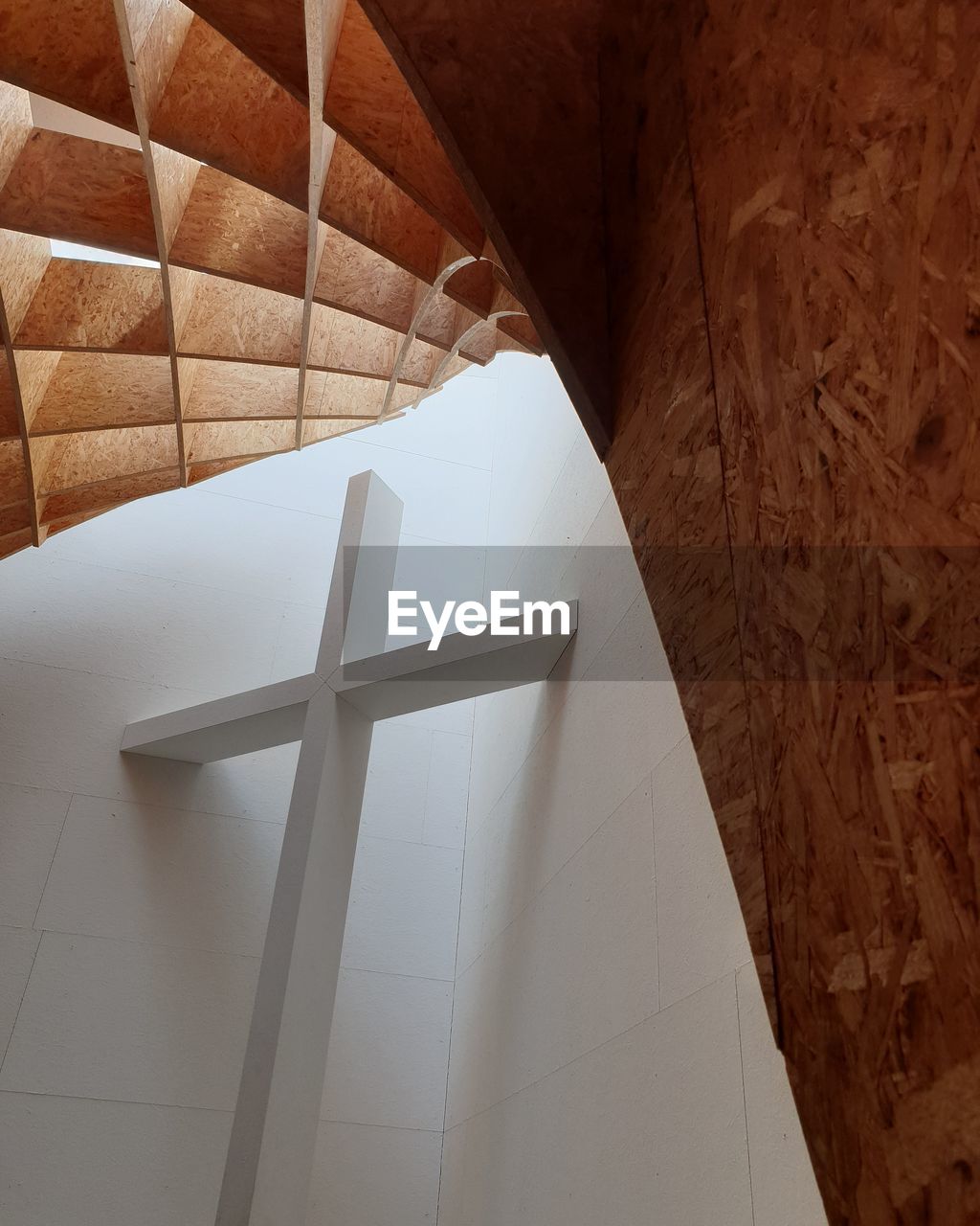 LOW ANGLE VIEW OF CROSS ON BUILDING WALL