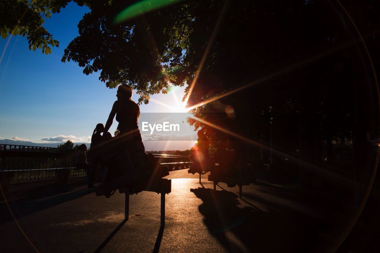 People in sunset playing on kids spring rides