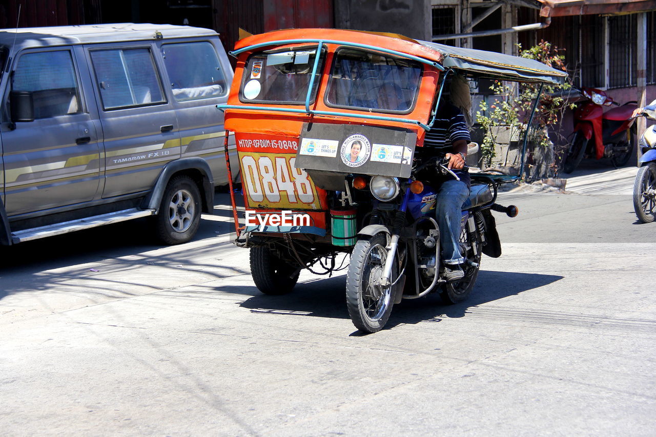 Man driving jinrikisha on city street