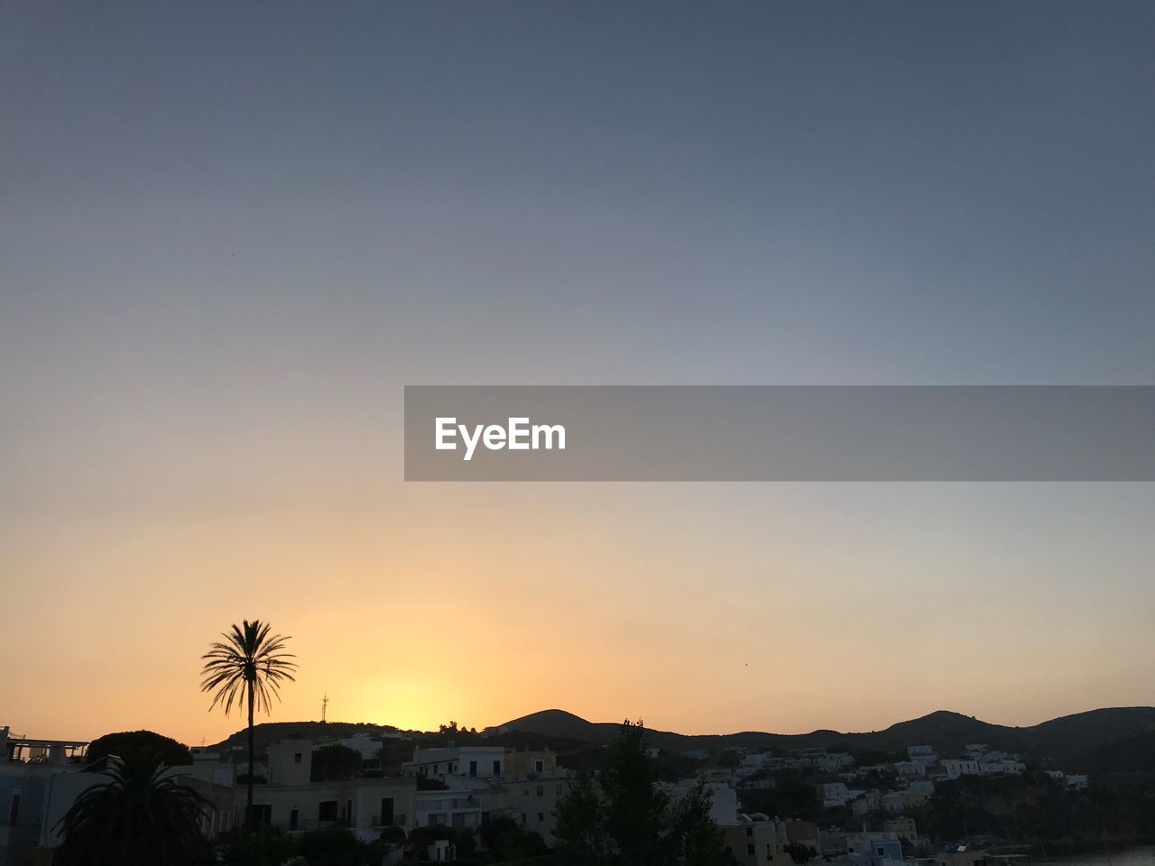 SILHOUETTE TREES AND BUILDINGS AGAINST CLEAR SKY DURING SUNSET