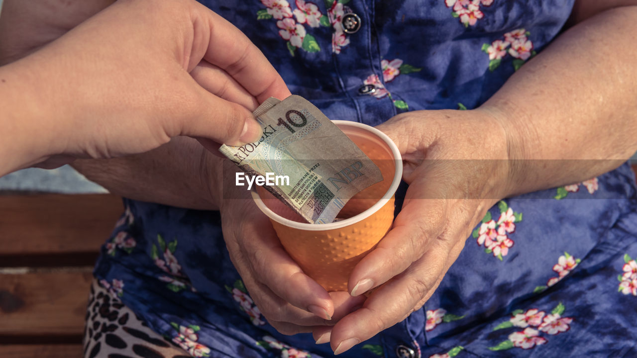 Cropped hand of person giving beggar paper currency