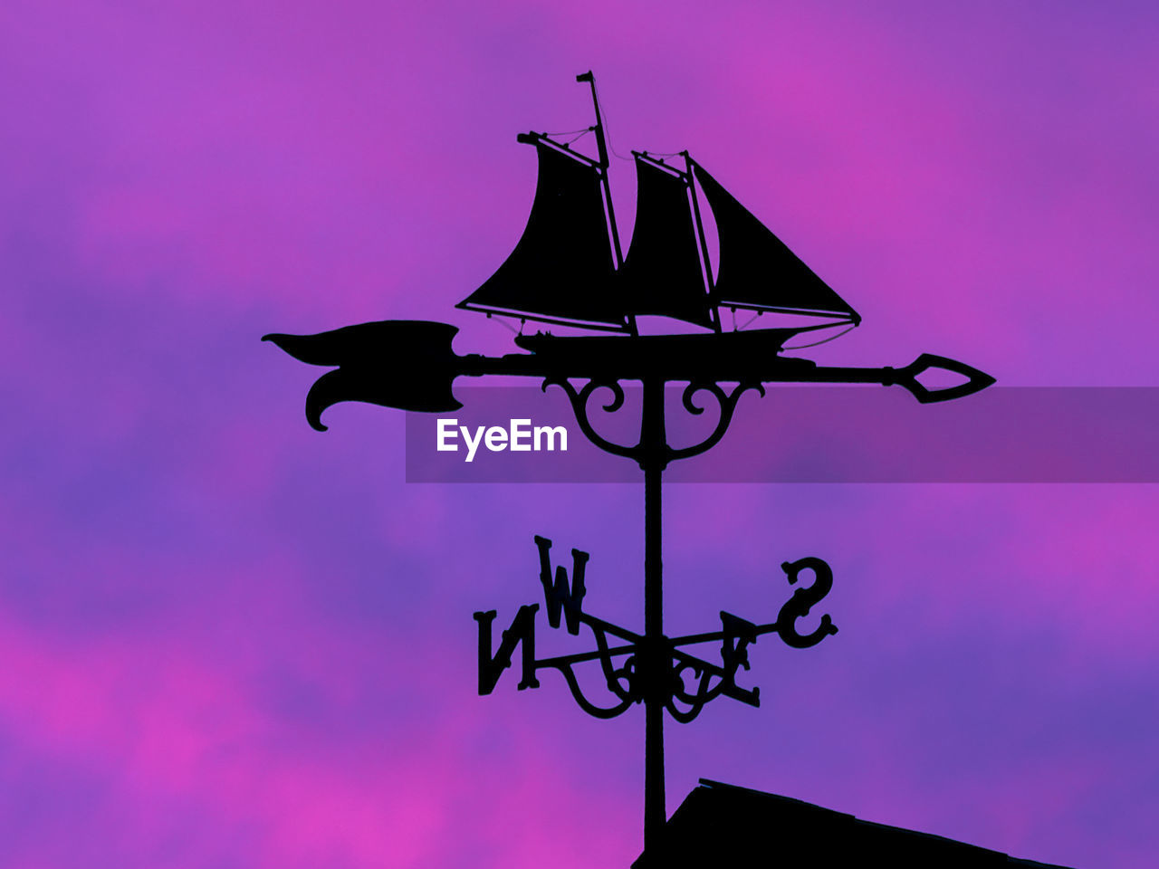 Low angle view of weather vane against sky during sunset