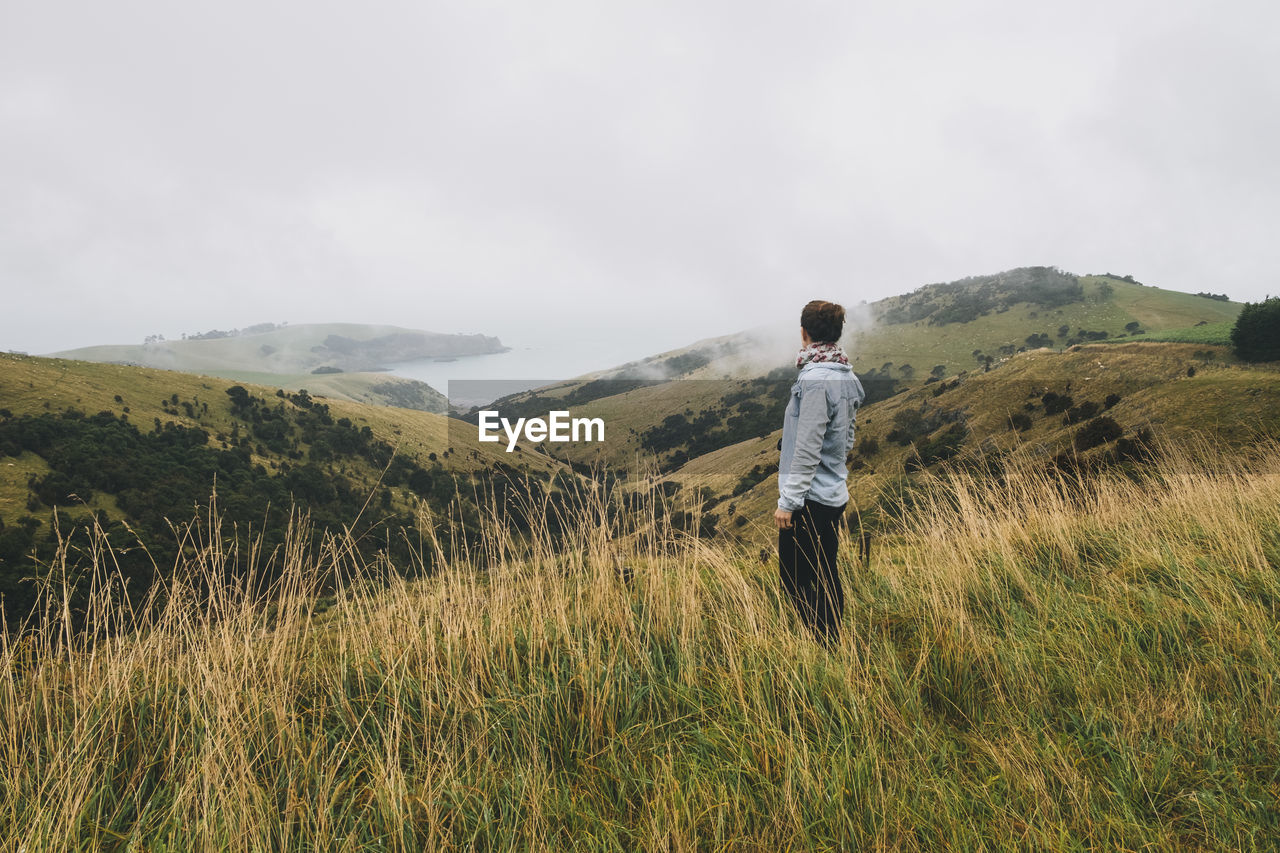 Woman on a blue shirt looking at the scenery, banks peninsula, nz