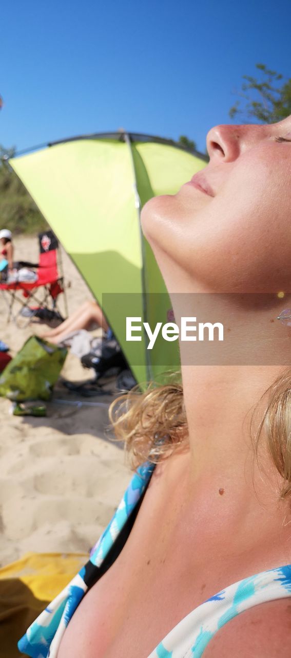 Midsection of woman at beach during sunny day