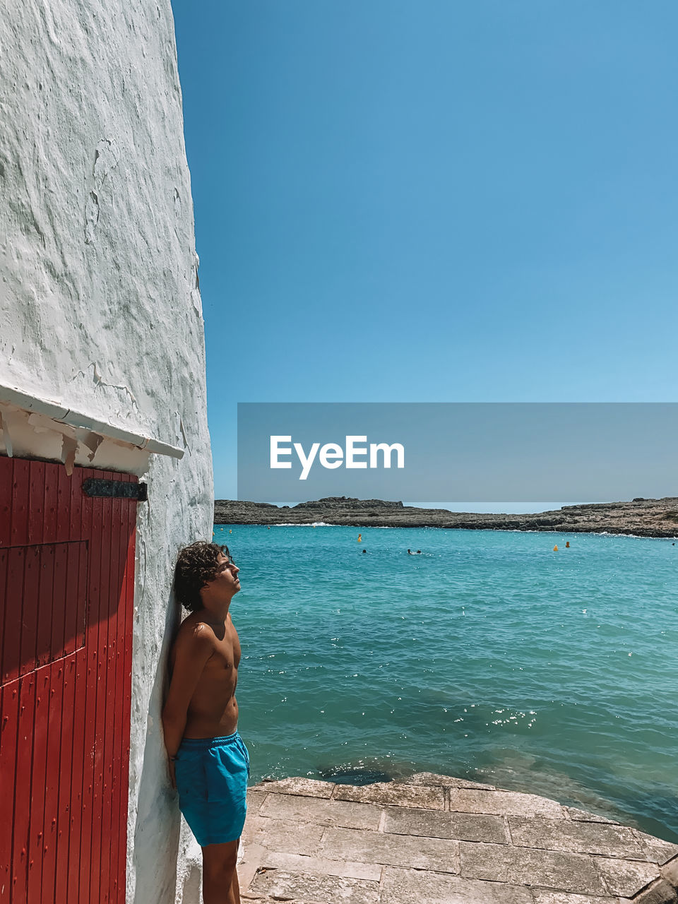 Man standing by sea against blue sky