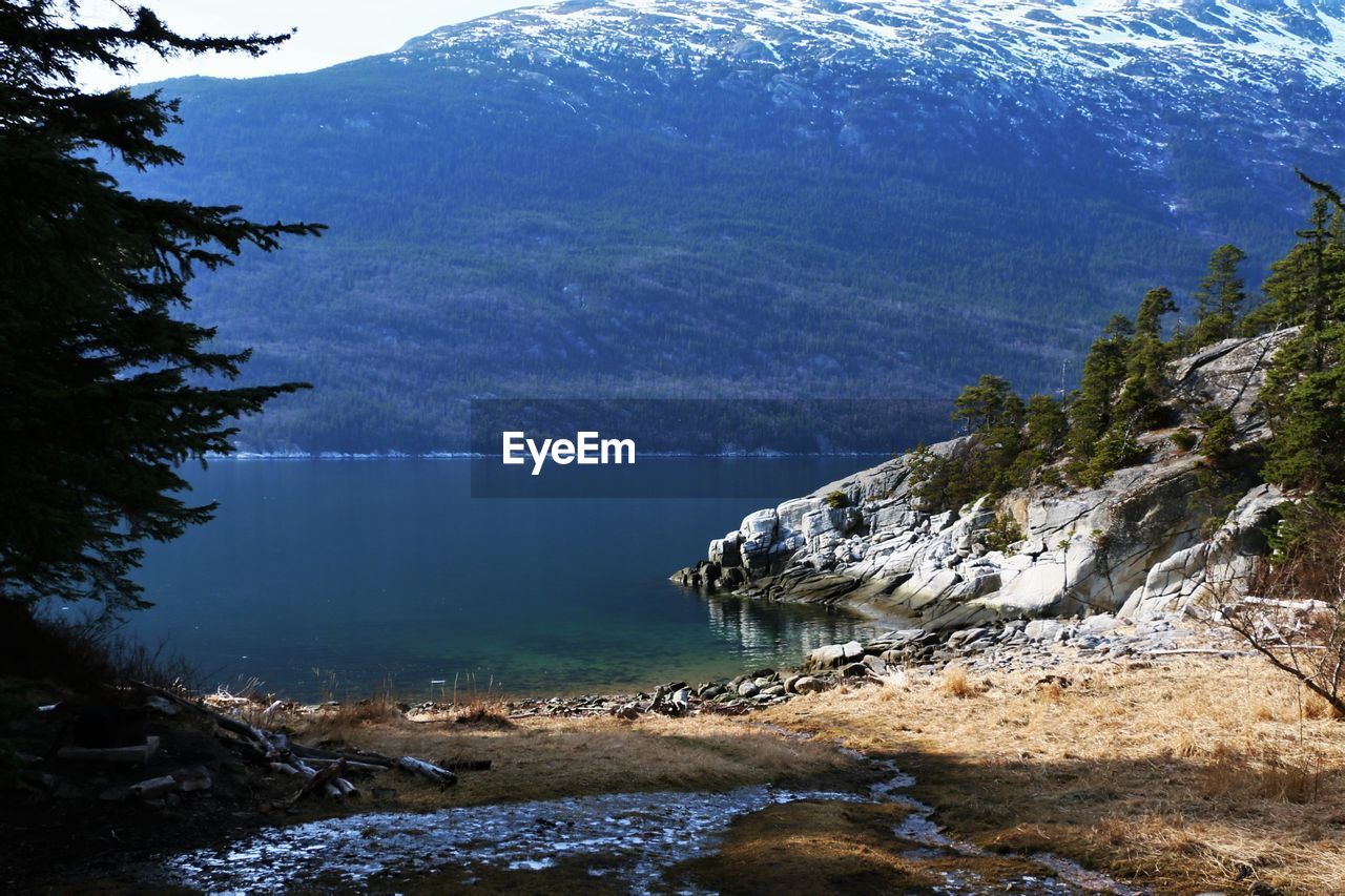 Scenic view of sea by mountains against sky