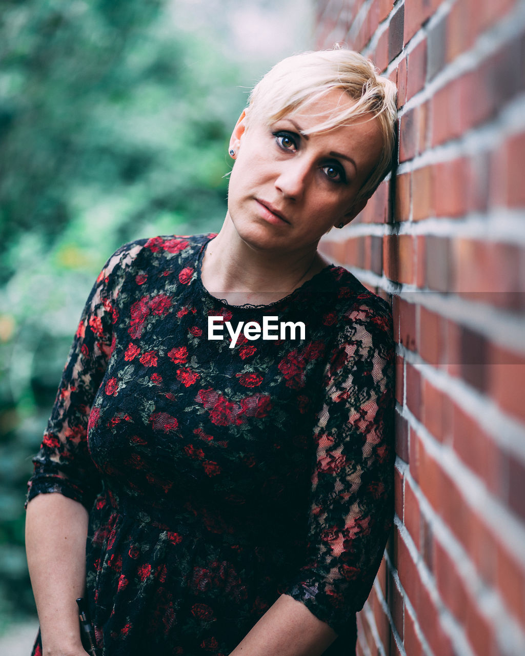 Portrait of beautiful woman standing by brick wall