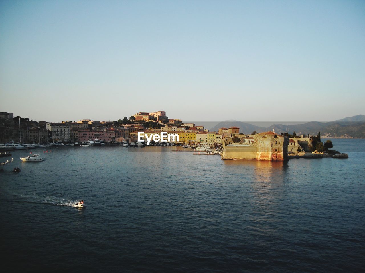 VIEW OF TOWNSCAPE BY SEA AGAINST CLEAR SKY