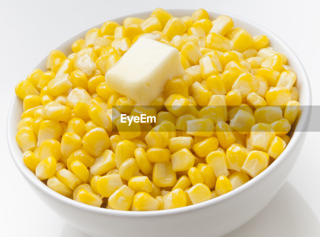 High angle view of corm and butter in bowl against white background