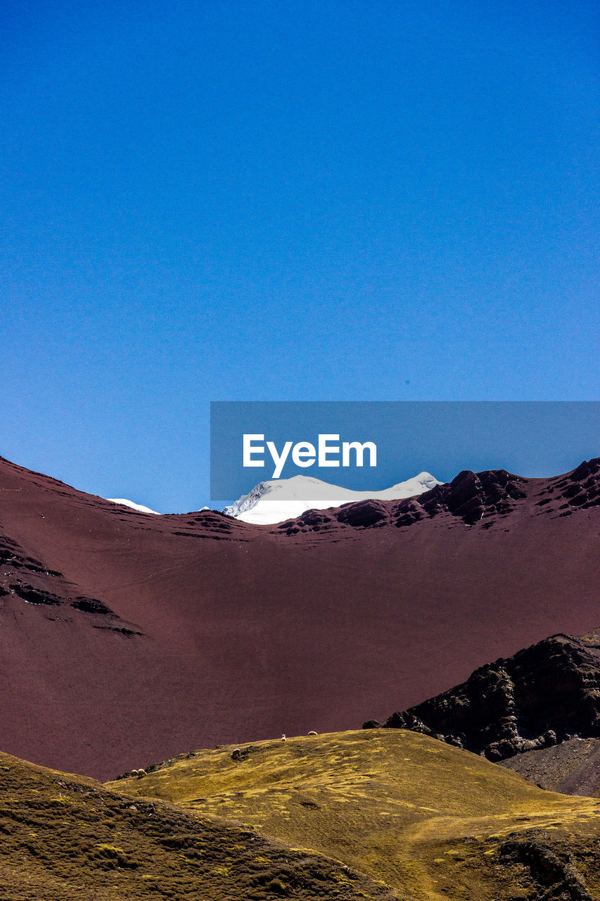 Scenic view of snowcapped mountains against clear blue sky