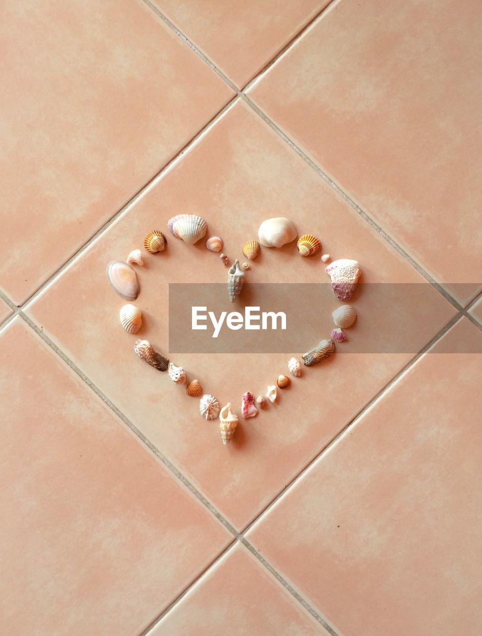 High angle view of heart shape made by seashells on tiled floor