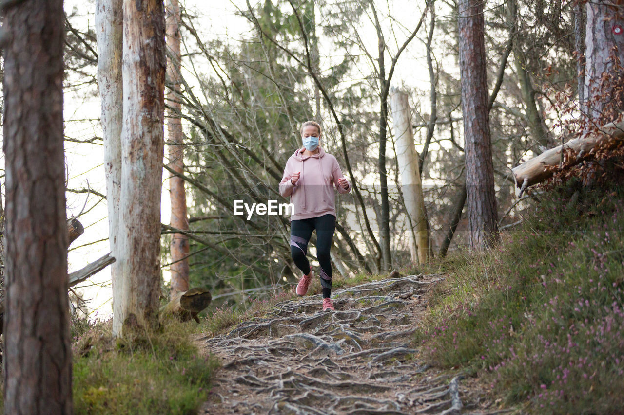 FULL LENGTH OF MAN RUNNING ON TREE TRUNK