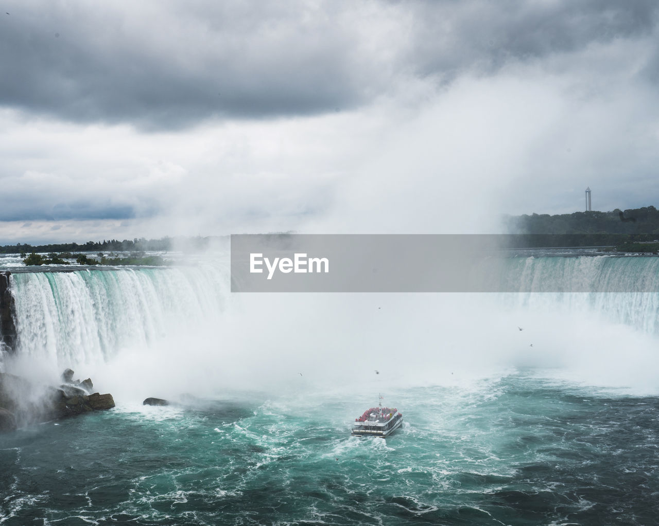 Scenic view of waterfall against cloudy sky