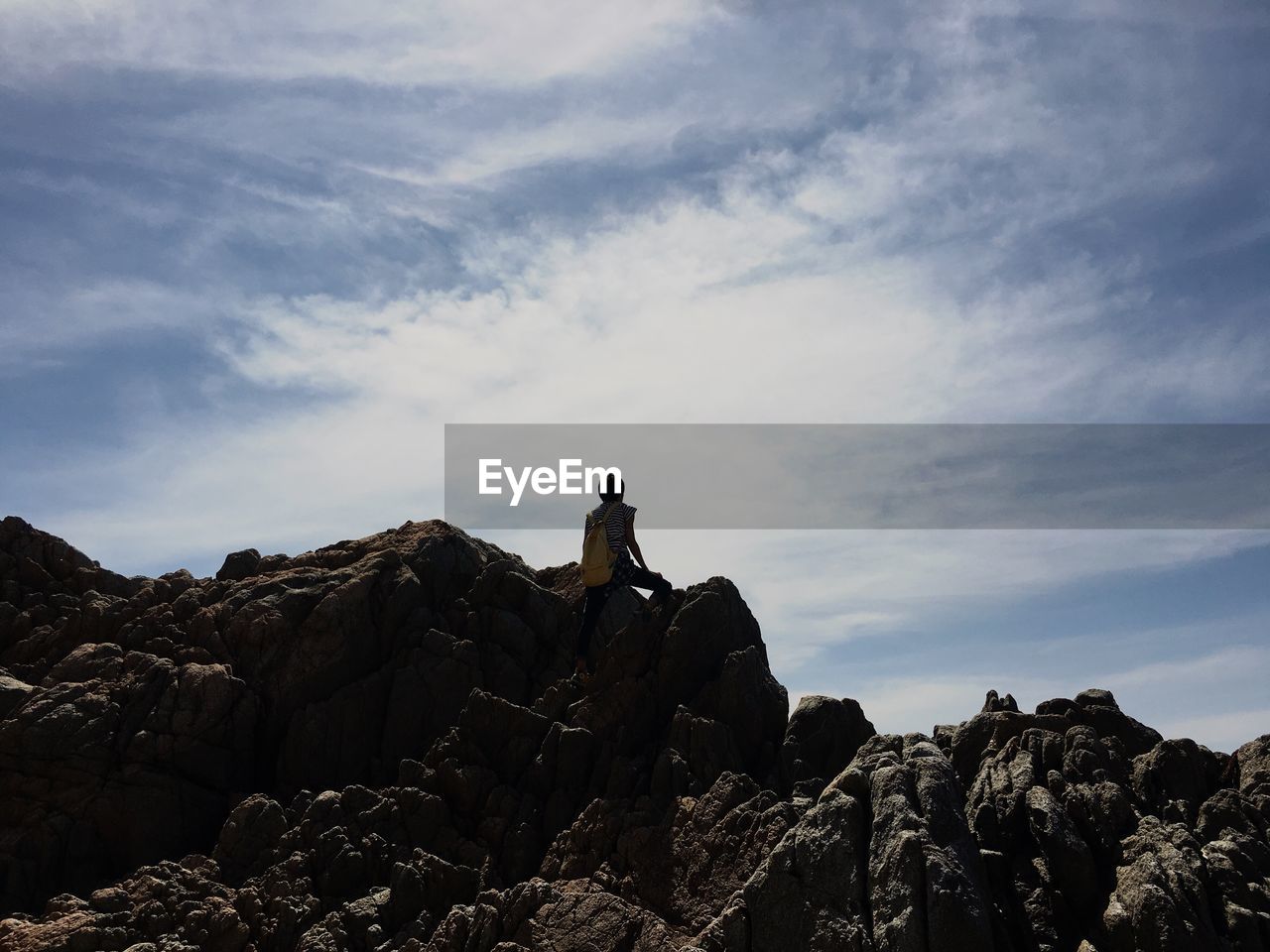 Low angle view of person on rock formation against sky