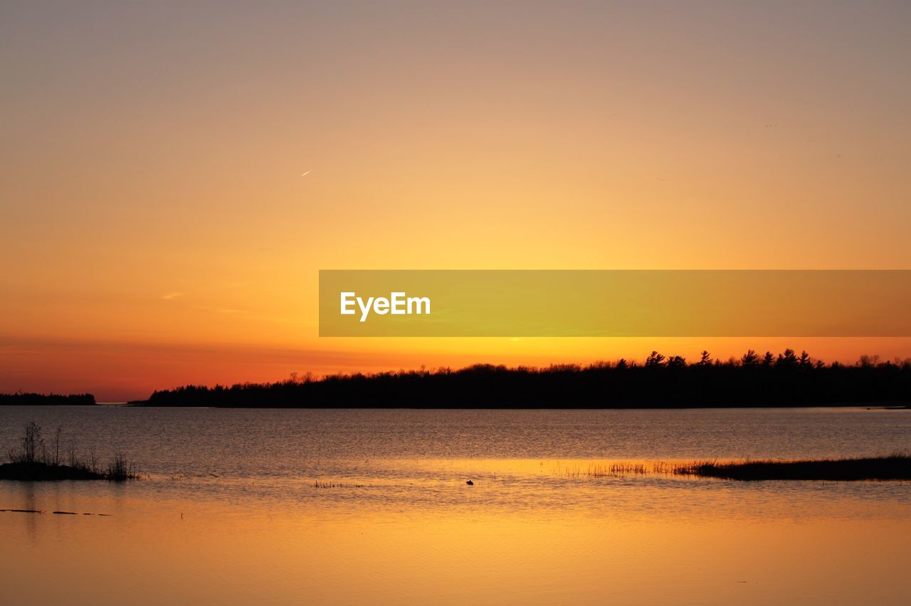 SCENIC VIEW OF LAKE AGAINST ORANGE SKY DURING SUNSET