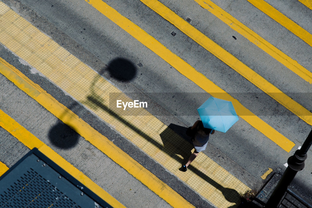 High angle view of woman holding umbrella while walking on street