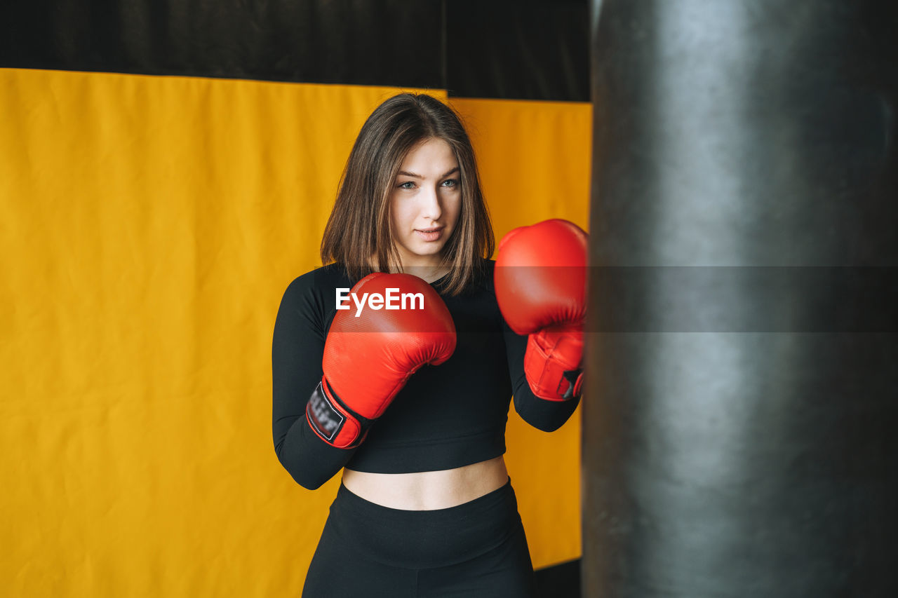 Young brunette woman in black wear engaged boxing training in fitness club gym