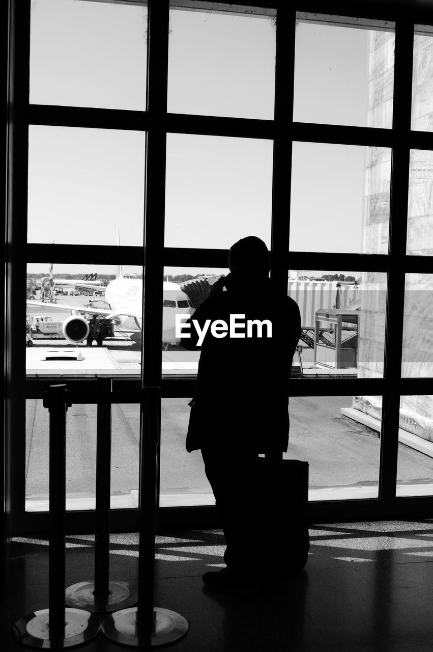 Silhouette man standing by window at airport