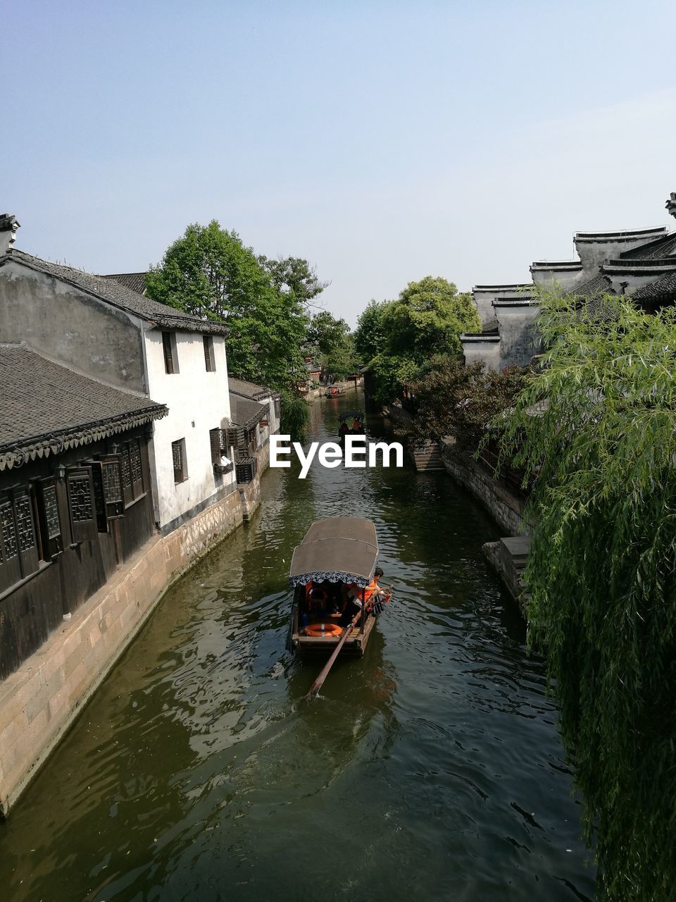 Boats in canal amidst buildings against clear sky