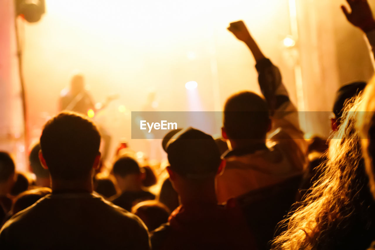 Cheering crowd and stage lights with space for your text. silhouette of people raise hand up 