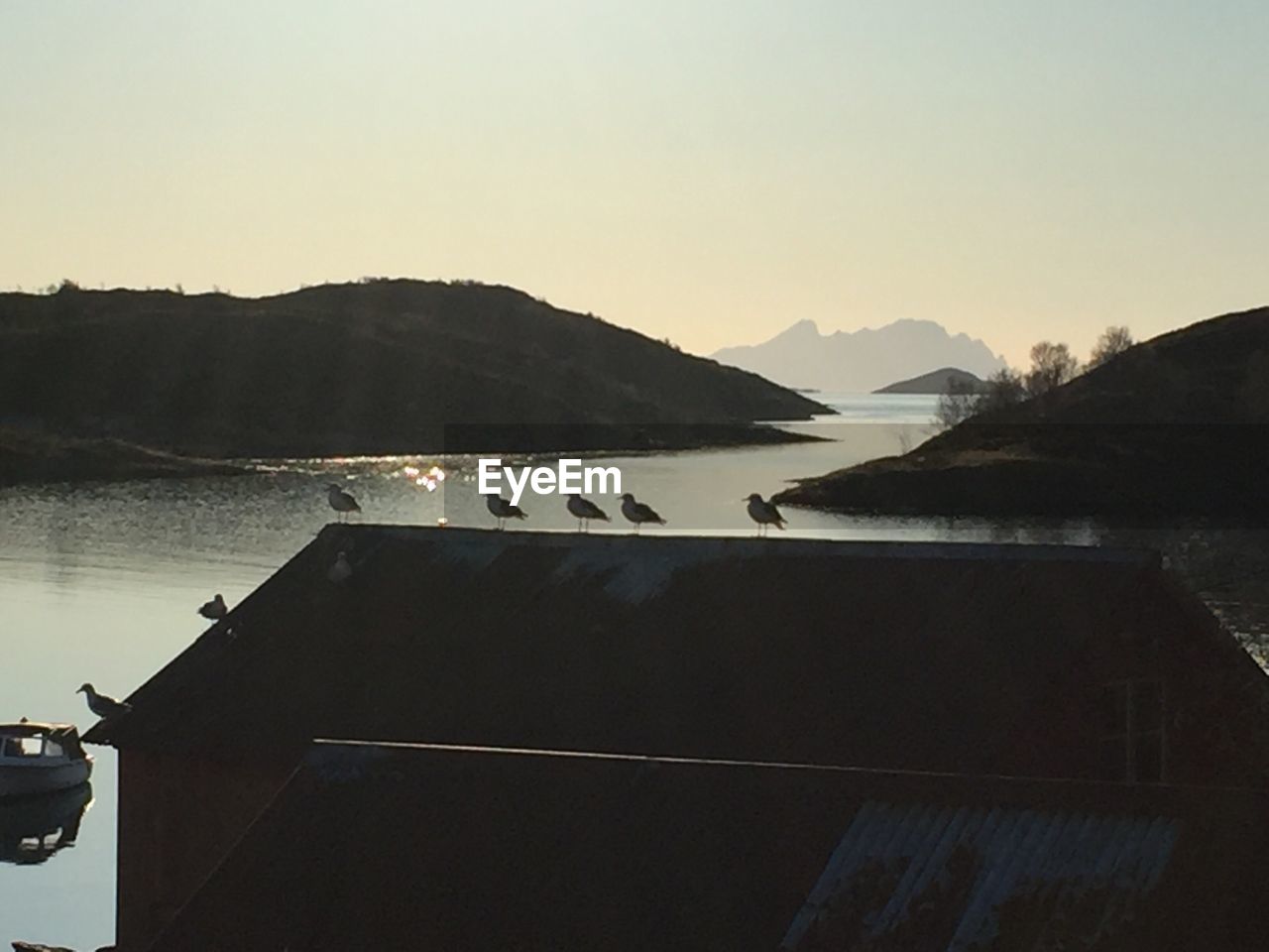 SILHOUETTE MOUNTAIN BY LAKE AGAINST CLEAR SKY