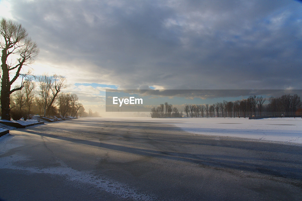 Snow covered landscape against cloudy sky