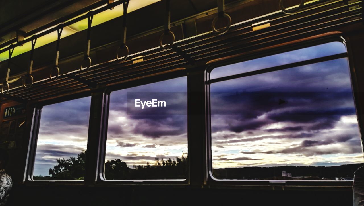 LOW ANGLE VIEW OF TRAIN AGAINST SKY SEEN THROUGH WINDOW