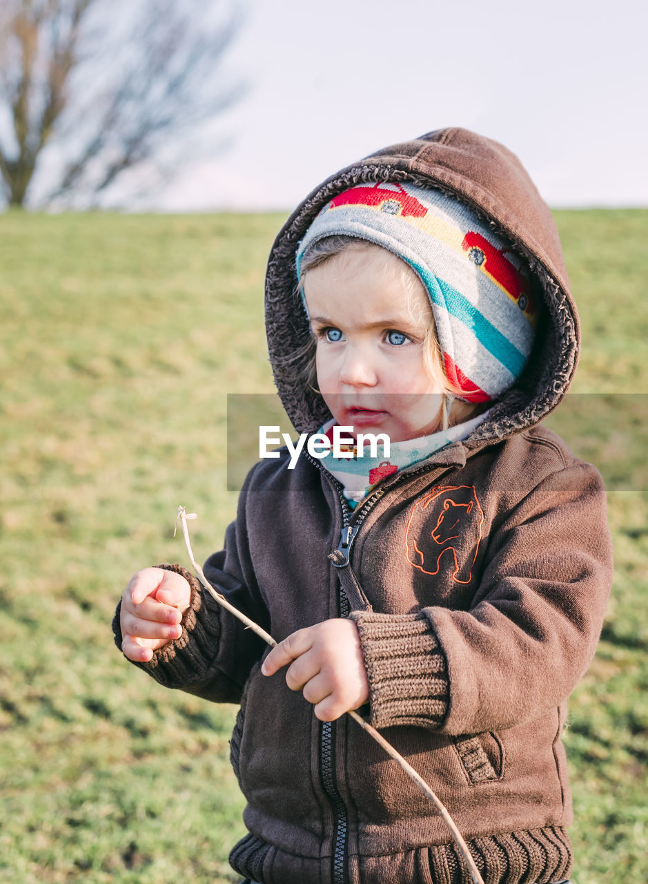 Cute girl looking away while standing on field