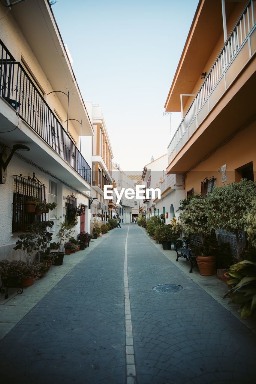 Empty road amidst buildings against clear sky