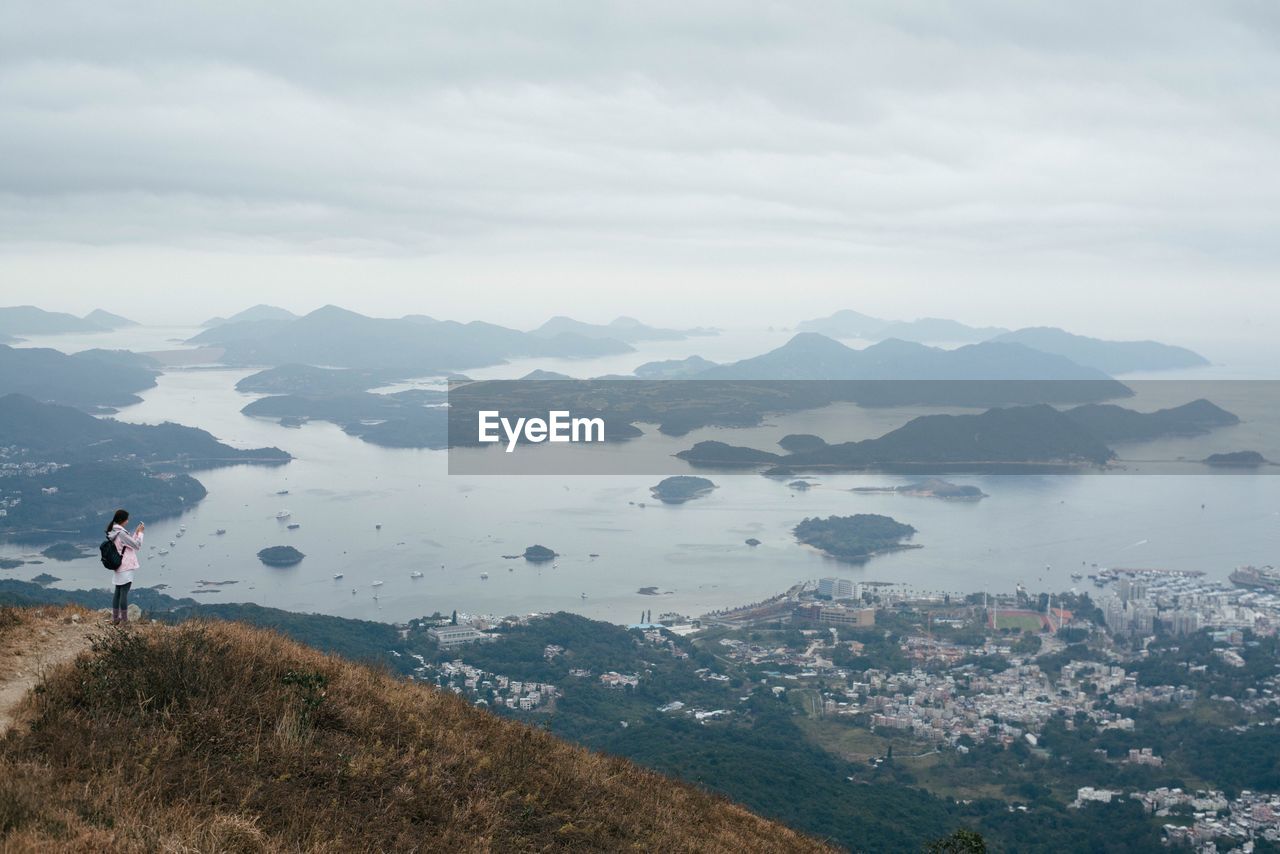 Side view of young woman on mountain against cloudy sky