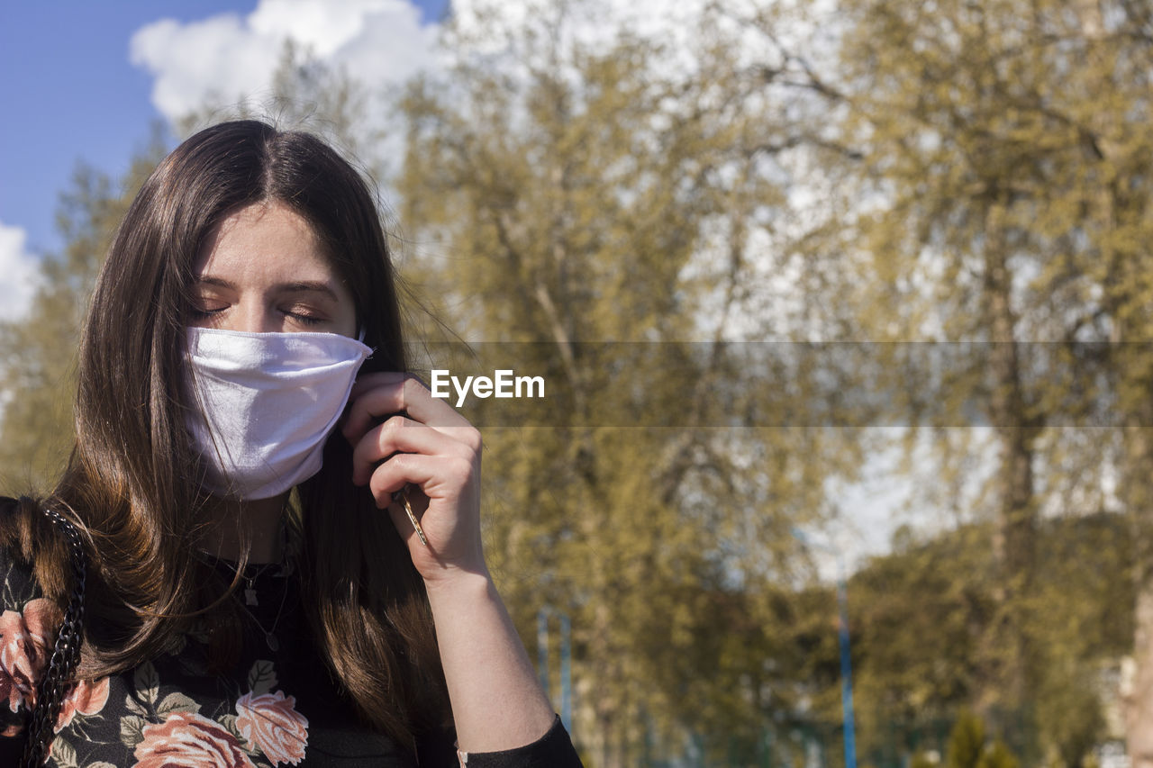 Close-up of woman wearing mask against trees in park