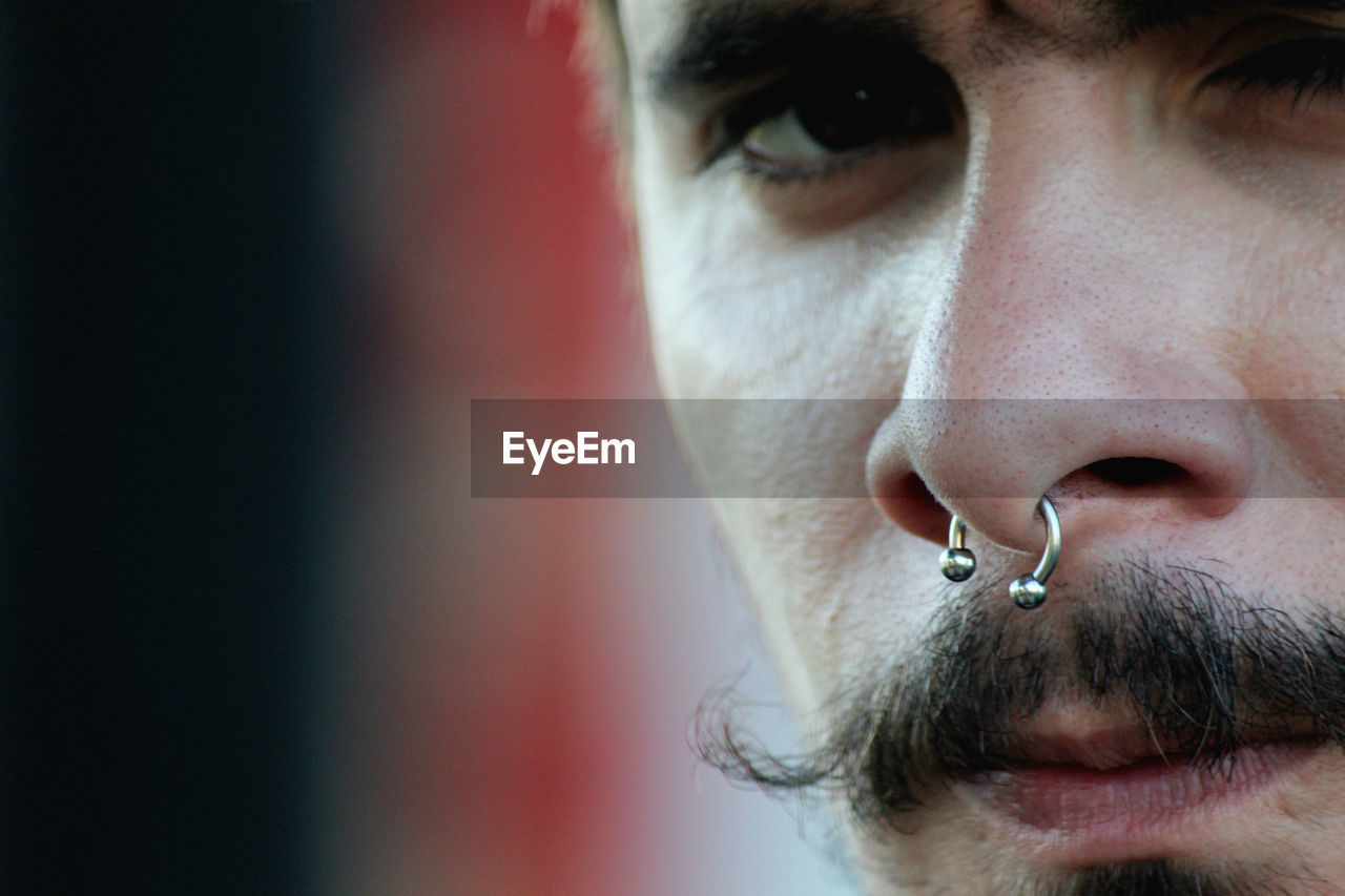 Close-up portrait of serous mid adult man wearing nose ring