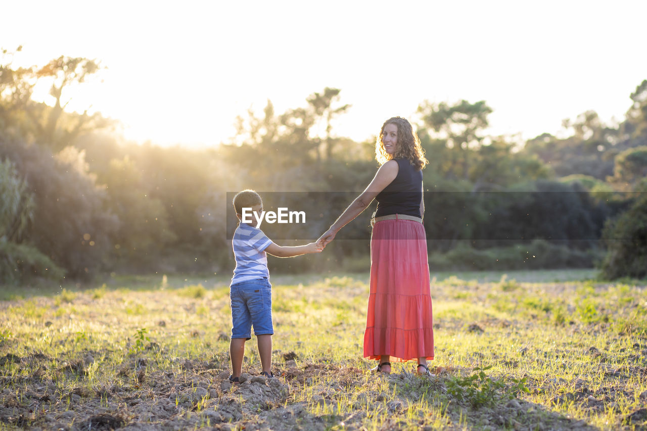 Woman and kid holding hands on a meadow