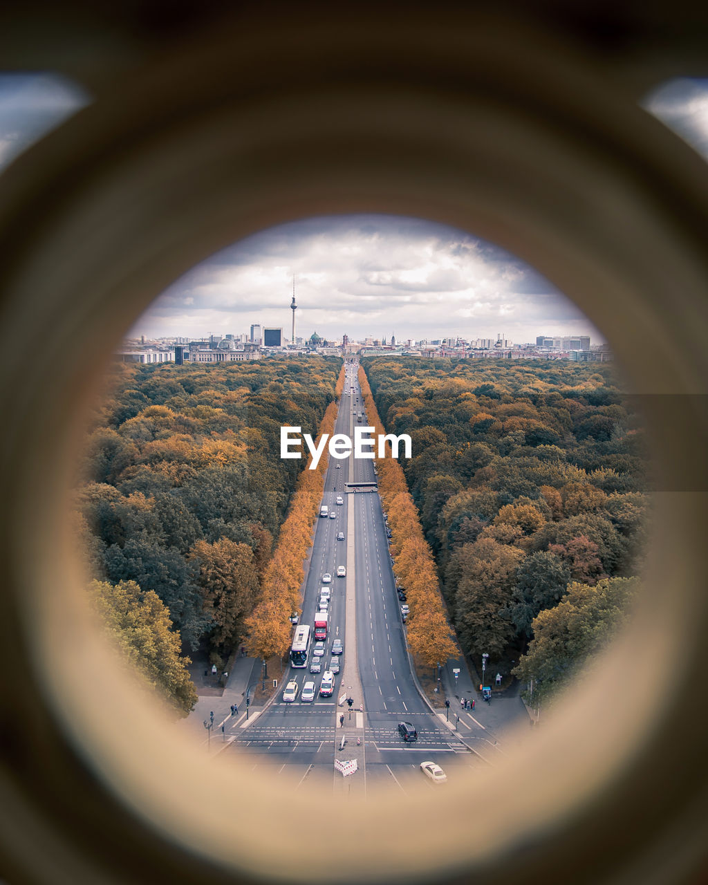 Road amidst trees seen through hole during autumn