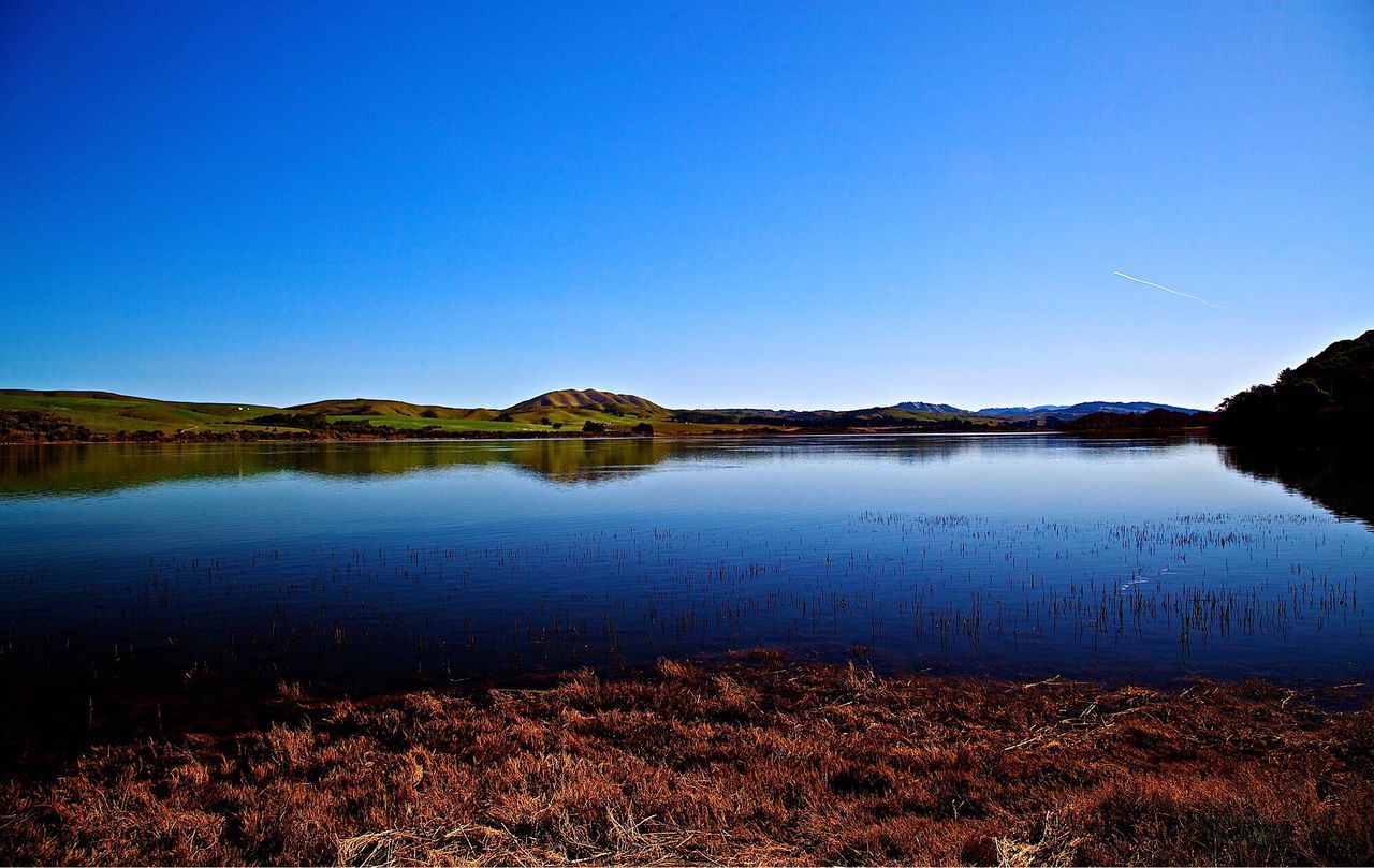 Scenic view of lake against clear blue sky